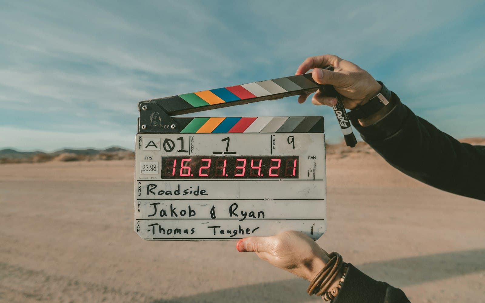 Hands holding a film clapperboard on a desert road