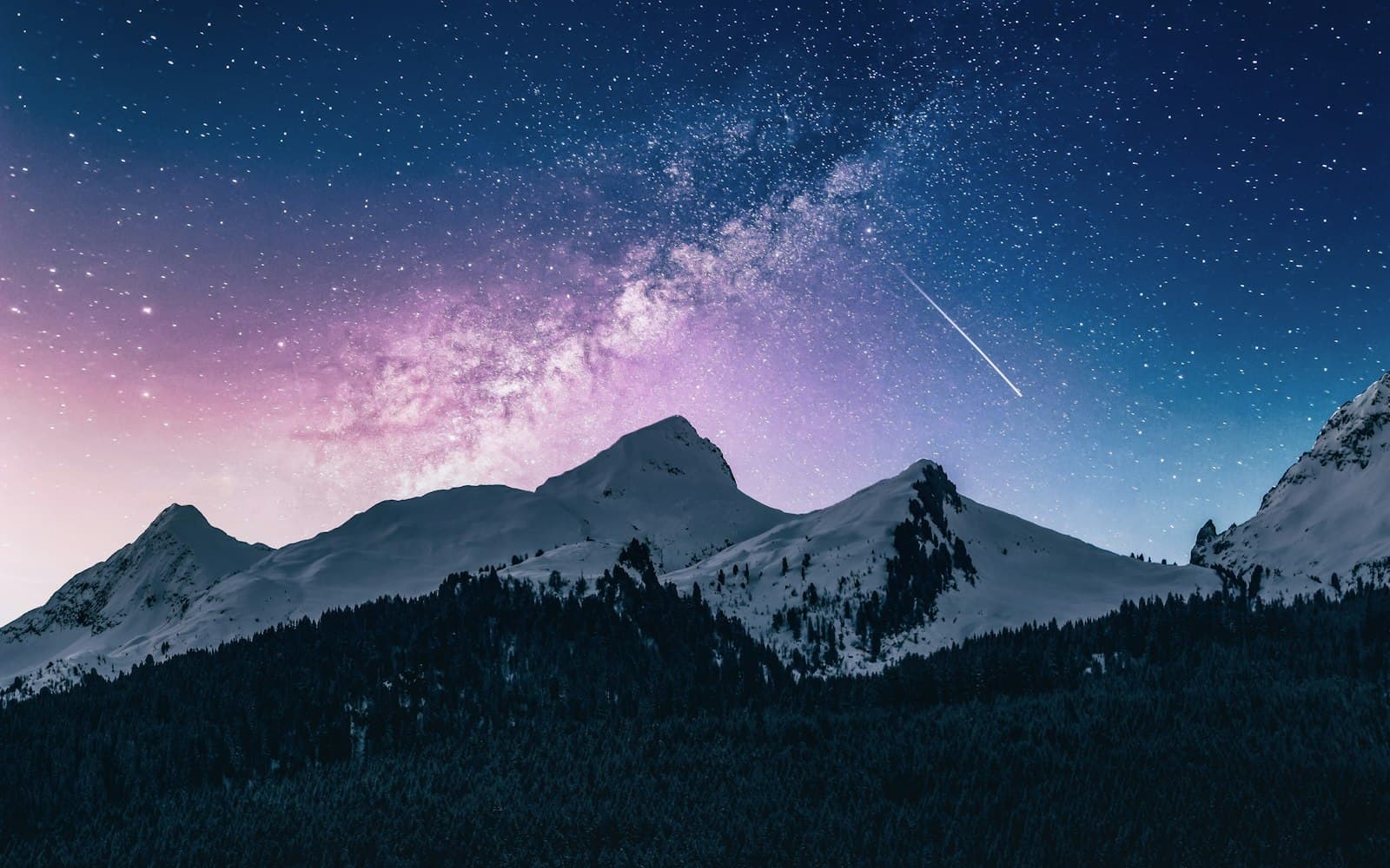 Snowy mountain peaks under the Milky Way, with a meteor crossing the sky
