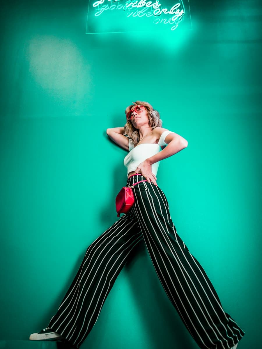 A fashion pose against a teal wall, useful as a vertical frame